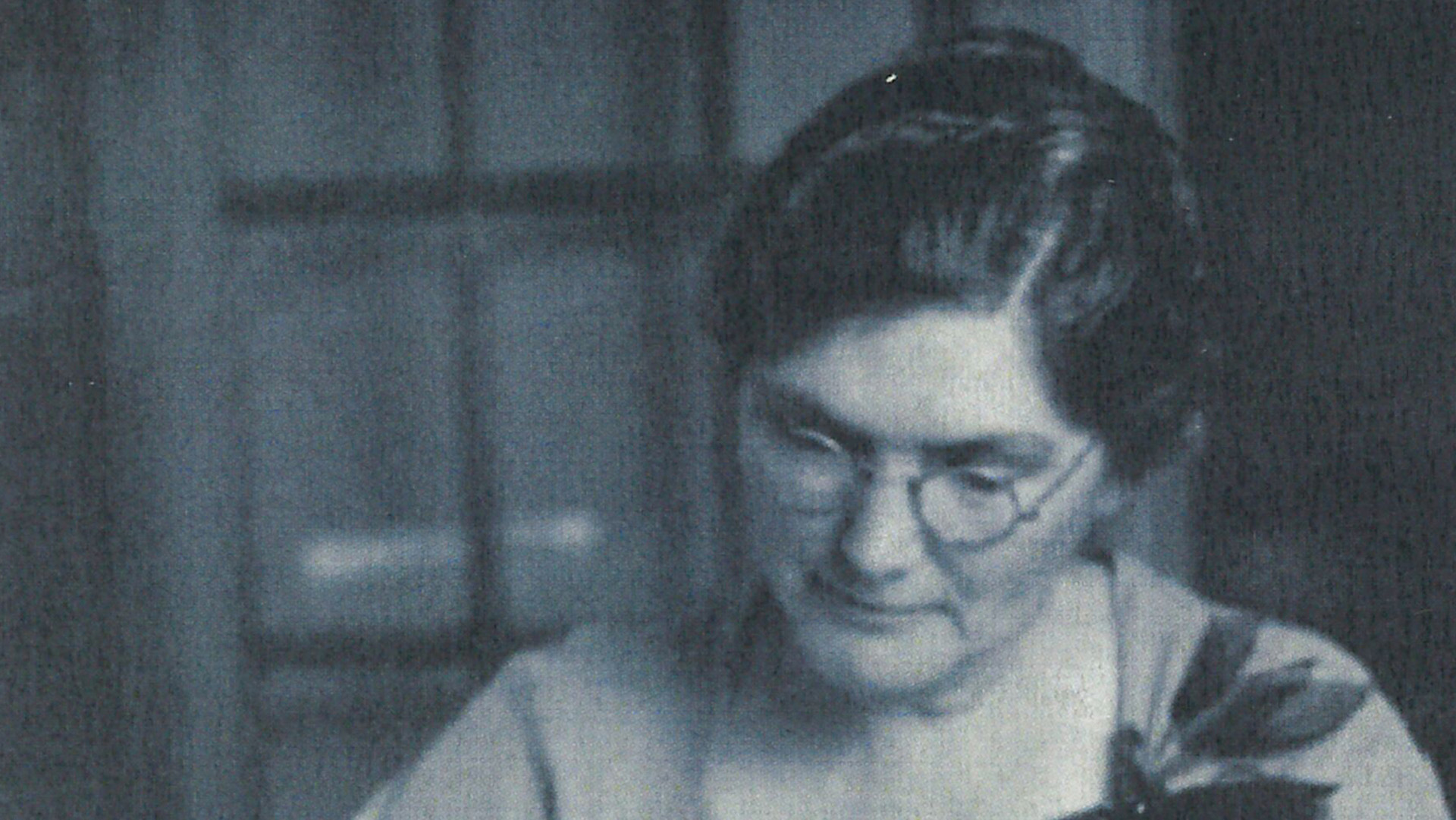 A vintage black and white photo of Ethel Harpst, a woman with glasses, looking downward in a reflective pose.